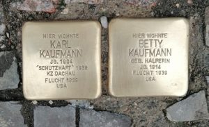 Zwei goldene Steine sind in den gehsteig einer Straße eingeladen. Auf ihnen steht eingraviert: Hier wohnte Karl Kaufmann" und "Hier wohnte Betty Kaufmann".