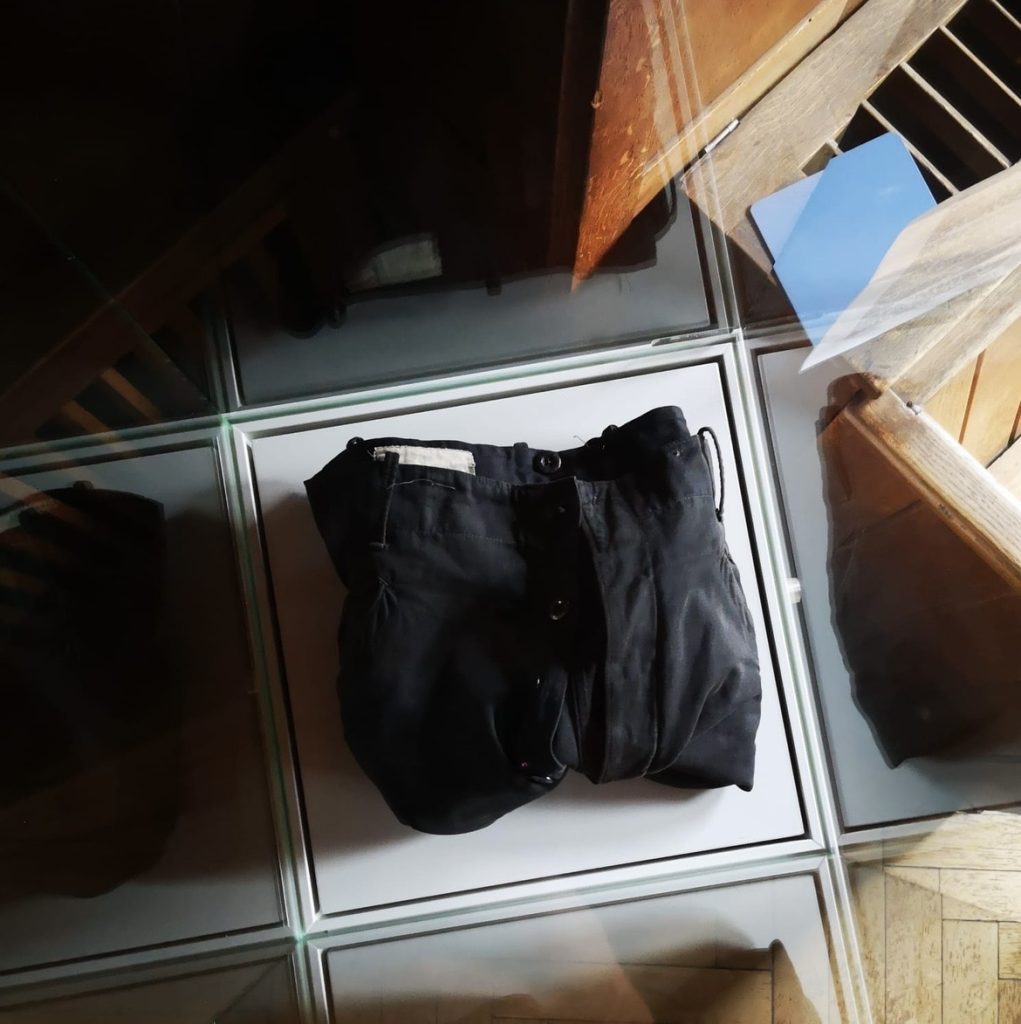 Eine dunkle Stoffhose liegt gefaltet auf einem weißen Hintergrund